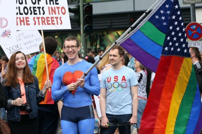 United States embassy employee Tim Standaert waves a rainbow American flag as he attends the Christopher Street Day (CSD) gay parade in Berlin on June 27, 2015. AFP PHOTO / ADAM BERRY