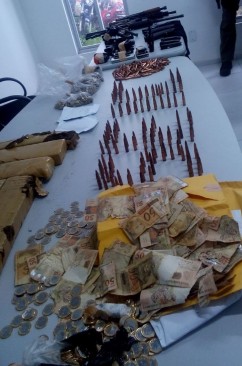Armas, muni&ccedil;&otilde;es, dinheiro e drogas apreendidos pela Pol&iacute;cia Civil com os dois suspeitos de agirem no roubo a institui&ccedil;&otilde;es financeiras.